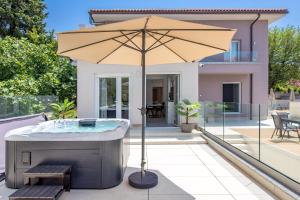 a hot tub with an umbrella in front of a house at VILLA MAR - LUXURY APARTMENTS with pool and hot tub in Selce, 20 meters from the beach, Boat tours option in Selce