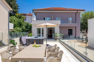 a patio with a table and chairs and an umbrella at VILLA MAR - LUXURY APARTMENTS with pool and Deluxe apartment with hot tub in Selce, 20 meters from the beach in Selce