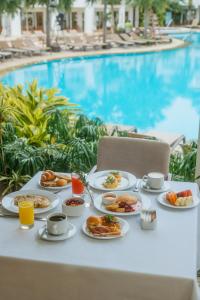 einen Tisch mit Teller mit Speisen neben einem Pool in der Unterkunft Los Tajibos, Santa Cruz de la Sierra, a Tribute Portfolio Hotel in Santa Cruz de la Sierra