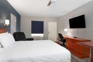 a bedroom with a bed and a desk and a television at Baymont by Wyndham Marianna in Marianna