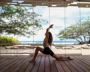 a woman doing a yoga pose in front of the beach at 99 Surf Lodge in El Limón