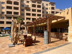 a patio with chairs and tables in front of a building at Apartment at Samarah Dead Sea Resort in Sowayma