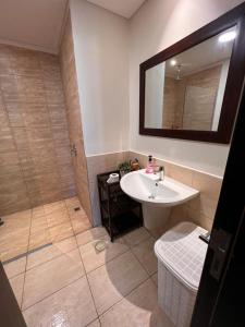a bathroom with a sink and a shower with a mirror at Apartment at Samarah Dead Sea Resort in Sowayma