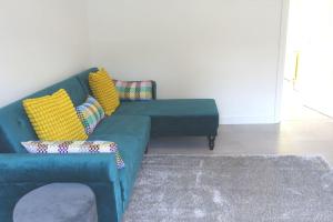 ein blaues Sofa mit gelben Kissen im Wohnzimmer in der Unterkunft The Reginald in Leeds