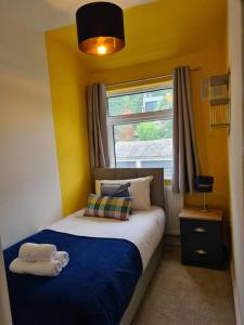 ein Schlafzimmer mit einem Bett mit einer blauen Decke und einem Fenster in der Unterkunft The Reginald in Leeds