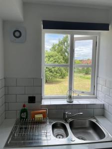 un lavello con finestra sopra di Grays Serviced Apartment a Stifford