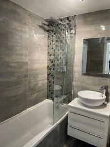 a bathroom with a sink and a glass shower at Grays Serviced Apartment in Stifford