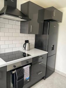a kitchen with a stainless steel refrigerator and gray cabinets at Grays Serviced Apartment in Stifford