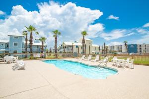 a swimming pool with lounge chairs and a resort at Sunrise Villa 101 - Pool & Boardwalk to the beach in Port Aransas
