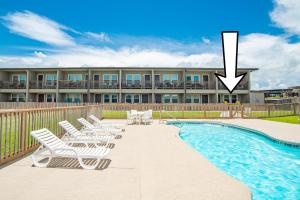 a swimming pool with lounge chairs next to a building at Sunrise Villa 101 - Pool & Boardwalk to the beach in Port Aransas