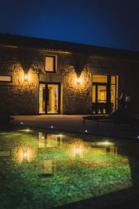 une maison avec une réflexion dans une piscine d'eau la nuit dans l'établissement Logis de l'Héronière, à Salles-sur-Mer