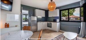 a kitchen with white cabinets and a table and chairs at Appartement Les Camélias proche La Rochelle in Périgny
