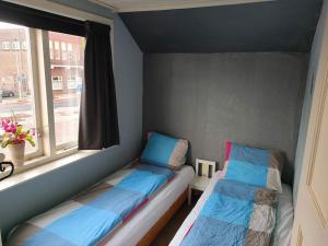 um pequeno quarto com 2 camas e uma janela em House with garden in the center close to the sea and Amsterdam em Beverwijk