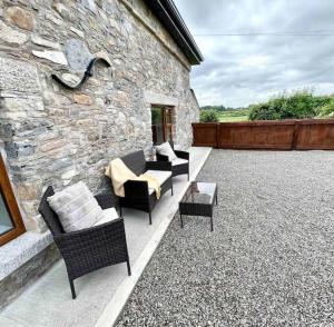 a patio with chairs and tables and a stone wall at Tom Rocky’s Farmyard in Templemore