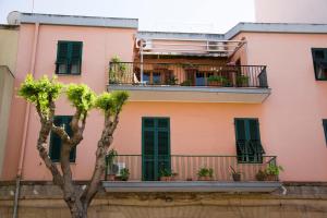 a pink building with a balcony with plants on it at B&B 55 Alghero in Alghero