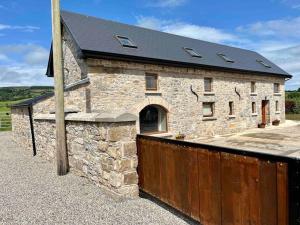 un edificio de piedra con una valla de madera delante de él en Tom Rocky’s Farmyard, en Templemore