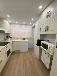 una cucina con armadietti bianchi e pavimenti in legno di Apartamentos Plaza del Arco a Caravaca de la Cruz Altre 2 foto