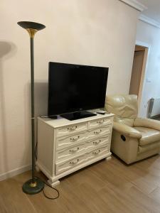 TV en un tocador con lámpara y sofá en Apartamentos Plaza del Arco en Caravaca de la Cruz