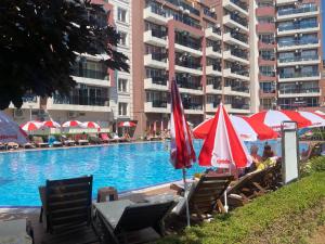 a swimming pool with chairs and umbrellas next to a building at ADMIRAL PLAZA C 43 Studio Sunny Beach in Sunny Beach