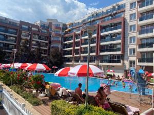 a pool with people sitting under umbrellas next to a building at ADMIRAL PLAZA C 43 Studio Sunny Beach in Sunny Beach