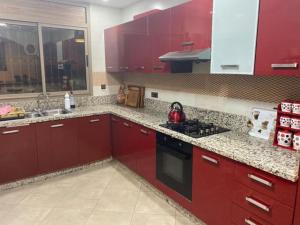 uma cozinha com armários vermelhos e um fogão preto em أكادير ايت ملول em Ait Melloul