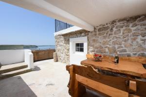 a dining room with a table and a stone wall at Holiday Stone House - Fumarea in Rtina