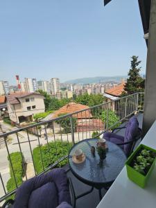 a balcony with a table and chairs and a view of a city at Apartman Daniela in Sarajevo