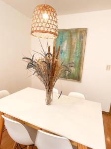 una mesa de comedor blanca con sillas y un jarrón. en Maravilloso ,amplío, gran ubicación dpto nuevo en Godoy Cruz