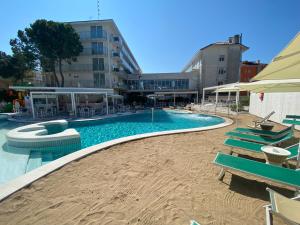 a swimming pool with chairs and umbrellas next to a building at Marina Palace Hotel 4 stelle S in Caorle