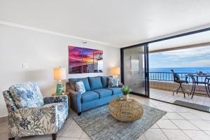 a living room with a blue couch and a balcony at Maui Kai 504 in Kahana