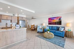 a living room with a blue couch and a kitchen at Maui Kai 504 in Kahana +16 photos