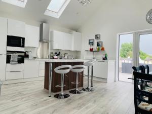 a kitchen with white cabinets and a counter with stools at Station House in Ballina