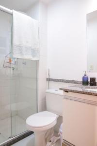 La salle de bains blanche est pourvue d'une douche et de toilettes. dans l'établissement Lindo Apt no Jd das Américas, à Cuiabá