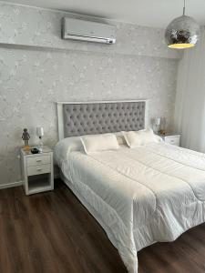 a white bedroom with a large bed and a night stand at Quartier Dorrego in Buenos Aires
