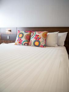 a bed with white sheets and colorful pillows at Hotel Britania Crystal Collection in Lima