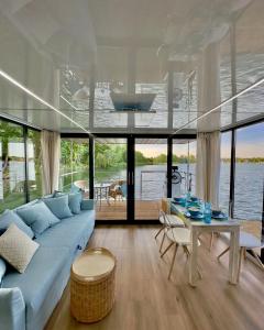 a living room with a blue couch and a table at Domki na wodzie - Resort 36 Houseboats in Giżycko
