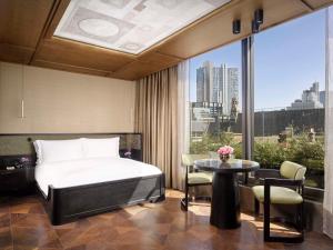 a bedroom with a bed and a table and a window at Nobu Hotel London Shoreditch in London