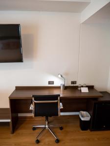 een bureau met een stoel en een televisie aan de muur bij Hotel Britania Crystal Collection in Lima