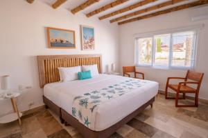 a bedroom with a large bed and two chairs at Atoq Paracas Reserva in Paracas