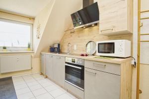 a kitchen with a stove and a microwave at Apartmentanlage Eldena Ferienwohnung 10 in Lobbe +15 photos