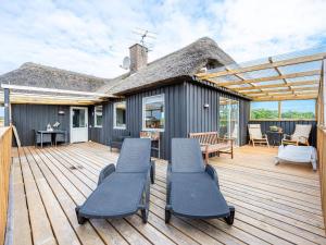eine Holzterrasse mit Stühlen und ein Haus in der Unterkunft Holiday home Hvide Sande LXIX in Havrvig