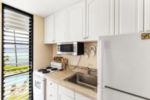 a kitchen with white cabinets and a sink and a refrigerator at Noelani 213 in Kapalua-West Maui Airport