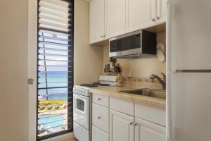 a kitchen with white cabinets and a sink and a microwave at Noelani 213 in Kapalua-West Maui Airport