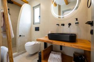 a bathroom with a sink and a toilet and a mirror at SunSal Luxury Studios - Sky in Naousa
