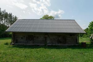 an old wooden cabin in a field of grass at Inn Kunai in Anykščiai