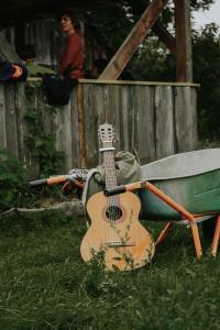 a guitar sitting on the grass next to a wheelbarrow at Inn Kunai in Anykščiai
