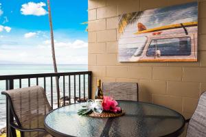 Noelani 201 في Kapalua-West Maui Airport: طاولة مع زجاجة من النبيذ والزهور على شرفة