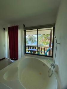 a large white bath tub in a room with a window at Ocean View Lodge in Cahuita
