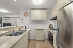 cocina con armarios blancos y nevera de acero inoxidable en Exclusive Stays - Southbank Tower, en Melbourne