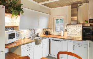 una cocina con armarios blancos y fregadero en The Woodpecker Cottage Tree en Salterød